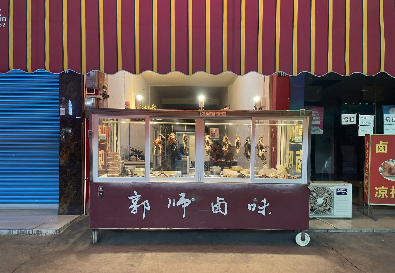 公义郭师卤味店面门头照片：红黄雨棚下挂着现卤的鸭子，摊车上写着郭师卤味